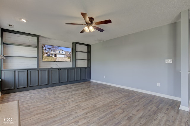 empty room featuring visible vents, baseboards, light wood finished floors, and a textured ceiling