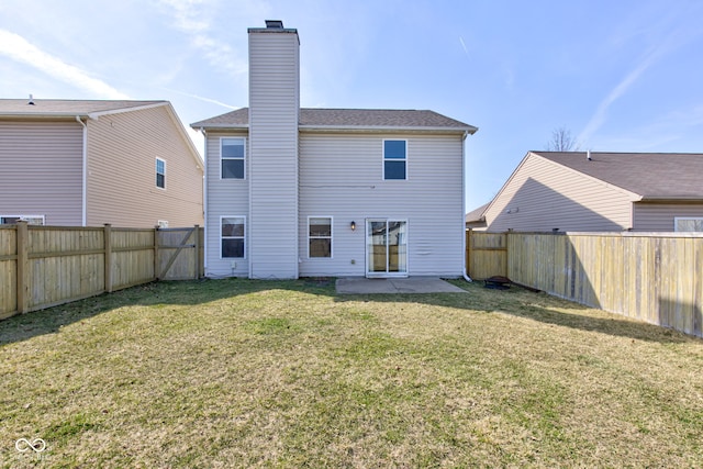 rear view of property with a lawn, a fenced backyard, and a chimney