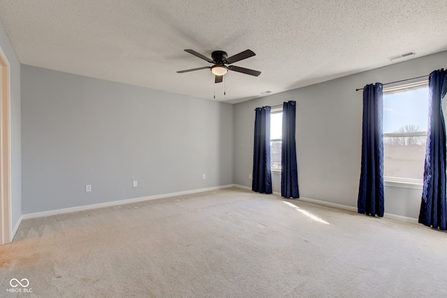 unfurnished room with visible vents, a ceiling fan, a textured ceiling, carpet flooring, and baseboards