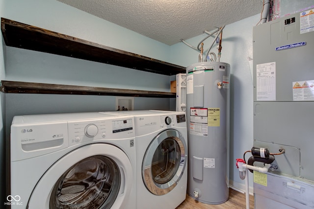 clothes washing area featuring heating unit, laundry area, separate washer and dryer, a textured ceiling, and electric water heater