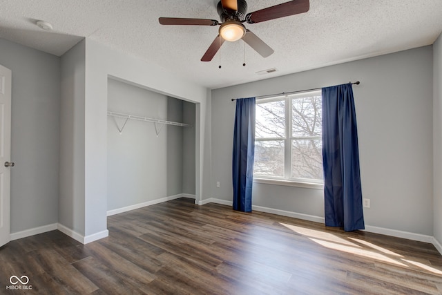 unfurnished bedroom featuring a closet, visible vents, baseboards, and wood finished floors