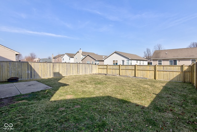 view of yard featuring a patio, a fenced backyard, and a residential view