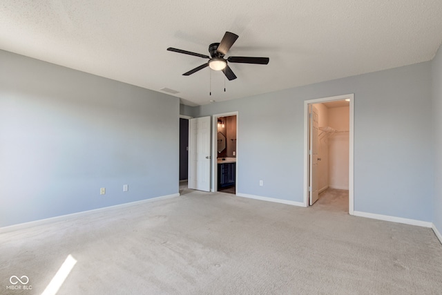 unfurnished bedroom with a walk in closet, baseboards, visible vents, and light carpet