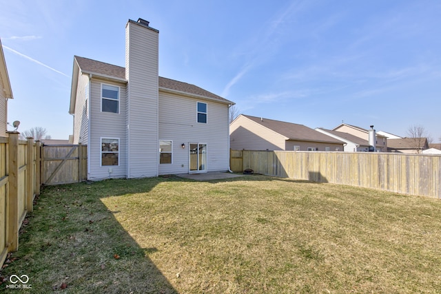 back of property featuring a lawn, a chimney, and a fenced backyard