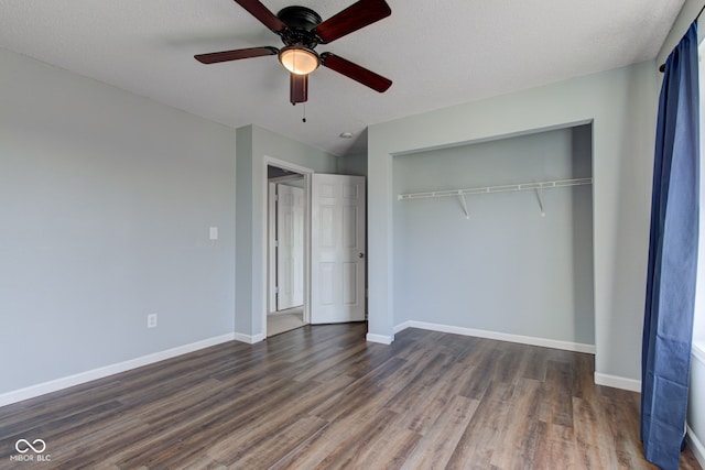 unfurnished bedroom with a closet, ceiling fan, dark wood-type flooring, and baseboards