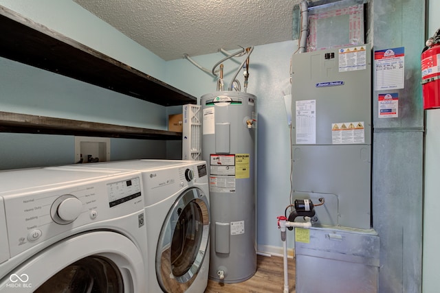 washroom featuring light wood-type flooring, washer and clothes dryer, a textured ceiling, water heater, and laundry area