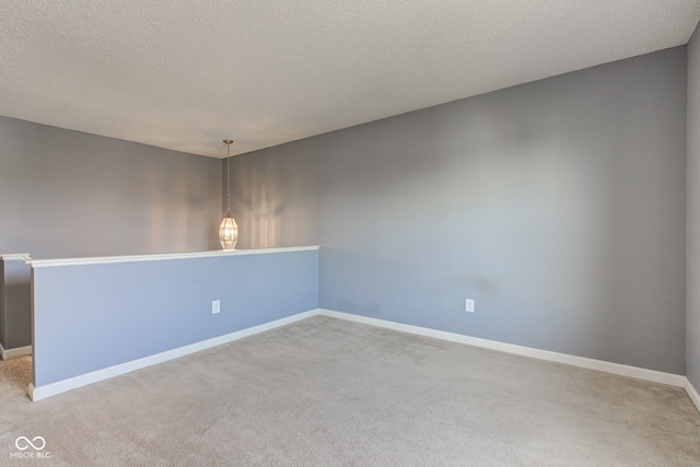 empty room with a textured ceiling, baseboards, and carpet floors