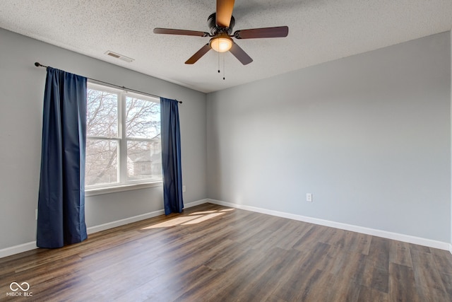 empty room featuring visible vents, a ceiling fan, a textured ceiling, wood finished floors, and baseboards