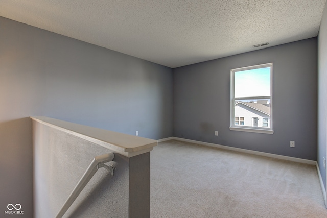 empty room featuring a textured ceiling, baseboards, visible vents, and light carpet