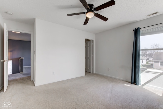 spare room with visible vents, a ceiling fan, a textured ceiling, baseboards, and light colored carpet