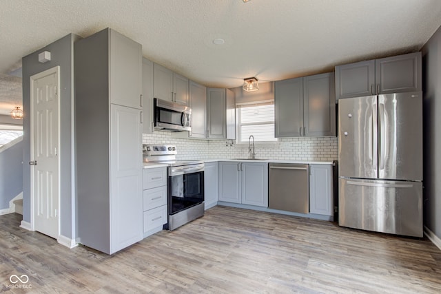 kitchen featuring a sink, stainless steel appliances, gray cabinets, and light countertops