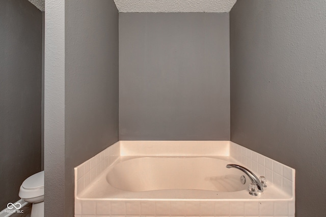 full bathroom featuring a textured wall, toilet, a bath, and a textured ceiling