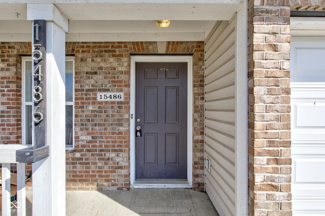 entrance to property featuring a garage and brick siding