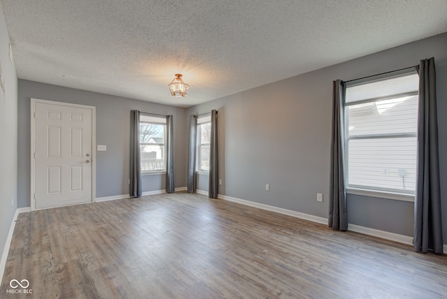 spare room featuring wood finished floors, baseboards, and a textured ceiling