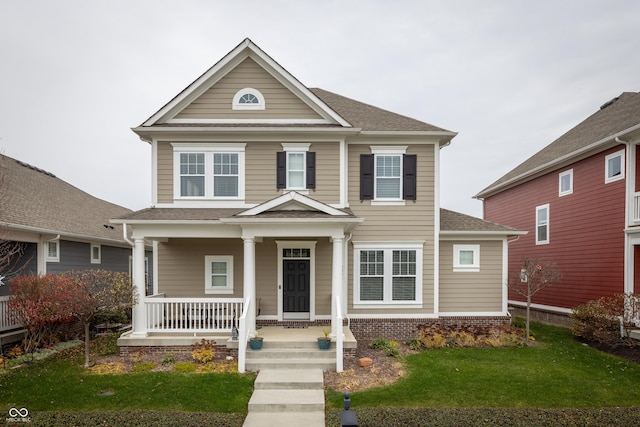 view of front of home with covered porch, a front lawn, roof with shingles, and brick siding