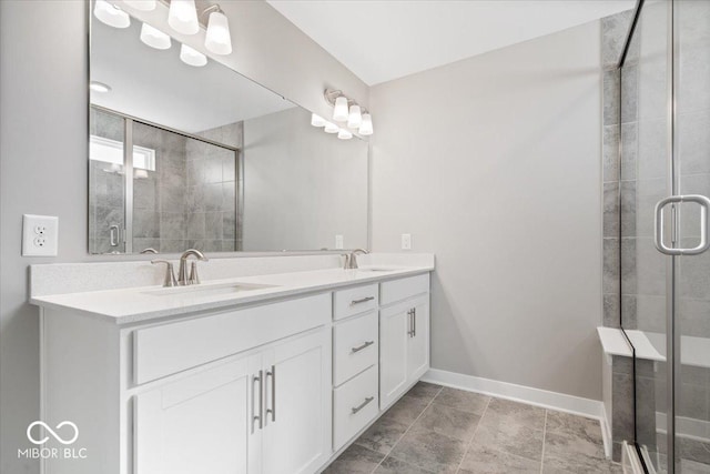 full bathroom with double vanity, a stall shower, a sink, and baseboards