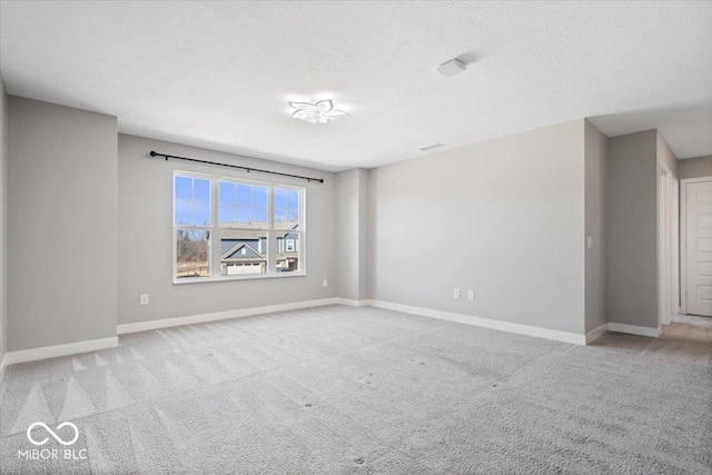 carpeted empty room with a textured ceiling and baseboards