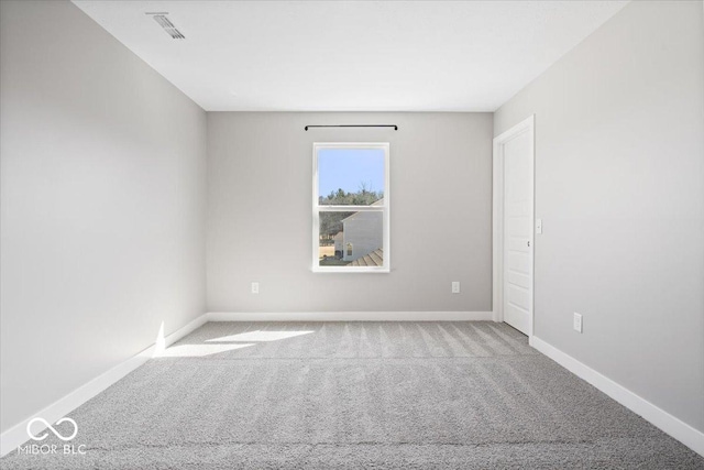 spare room featuring carpet floors, visible vents, and baseboards