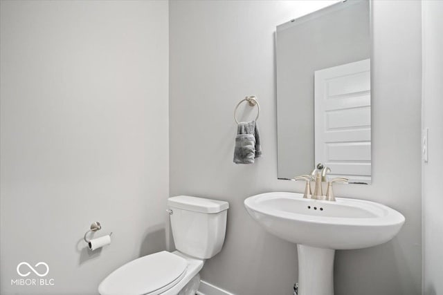 half bath with baseboards and toilet