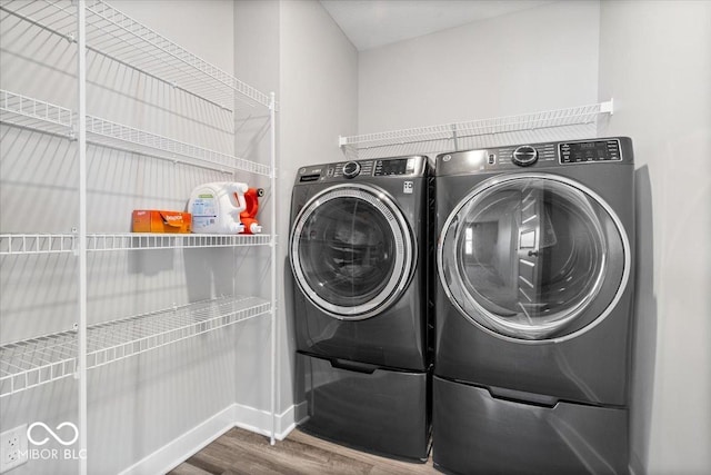 washroom featuring laundry area, wood finished floors, and washing machine and dryer