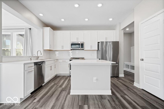 kitchen with appliances with stainless steel finishes, dark wood-type flooring, a sink, and tasteful backsplash