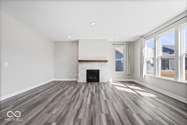 unfurnished living room with a tile fireplace, recessed lighting, wood finished floors, and baseboards