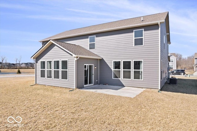 rear view of house featuring a patio, a shingled roof, a lawn, and cooling unit