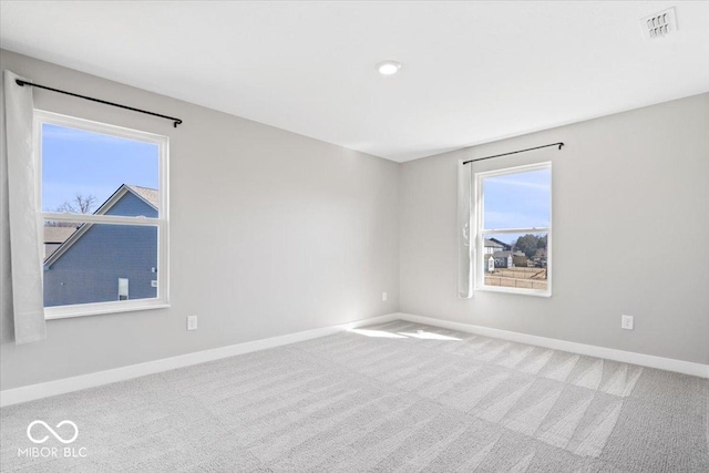 carpeted spare room featuring baseboards and visible vents