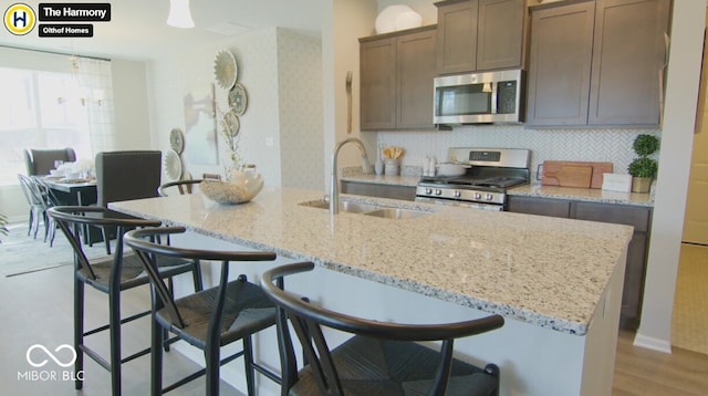 kitchen featuring pendant lighting, stainless steel appliances, a sink, an island with sink, and a kitchen breakfast bar