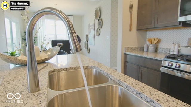 kitchen featuring appliances with stainless steel finishes, dark brown cabinets, decorative backsplash, and light stone countertops