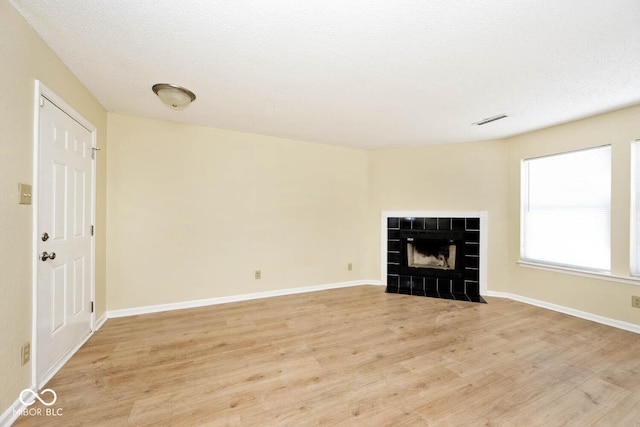 unfurnished living room with visible vents, a fireplace, light wood-style flooring, and baseboards