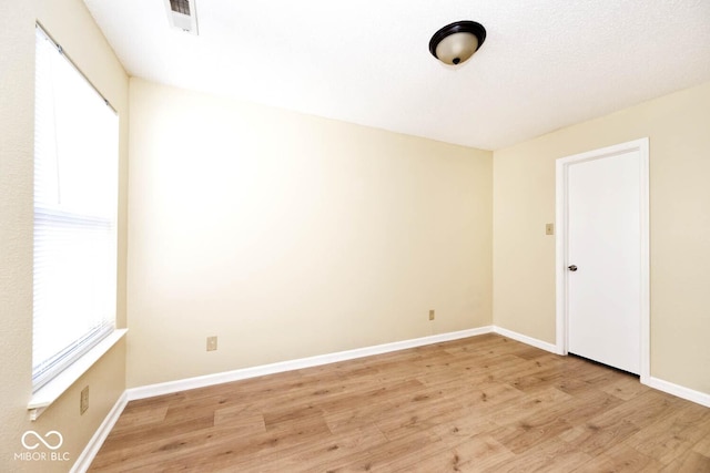 empty room with baseboards, light wood-style flooring, visible vents, and a wealth of natural light