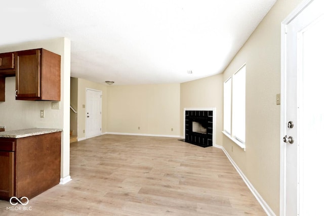 unfurnished living room with light wood-style floors, a fireplace, and baseboards