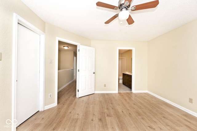 unfurnished bedroom with light wood-style floors, ceiling fan, baseboards, and ensuite bathroom