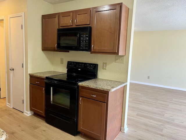 kitchen with light wood-style floors, baseboards, a textured ceiling, and black appliances