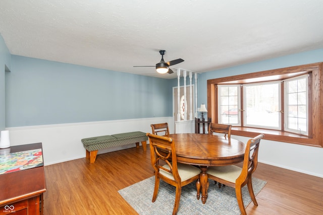 dining room featuring a ceiling fan, light wood-type flooring, a textured ceiling, and baseboards