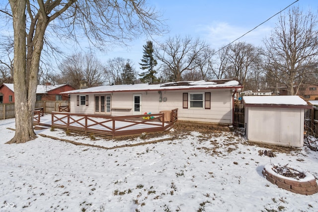 snow covered house with an outbuilding, fence, and a storage shed