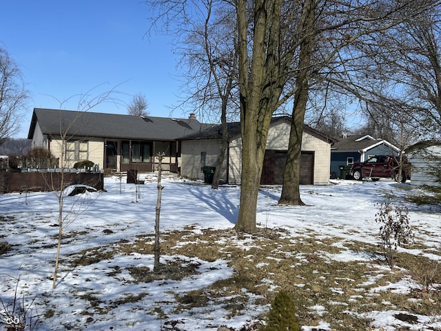 snow covered property featuring a sunroom and an attached garage