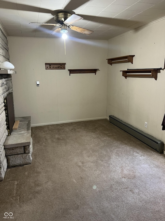 unfurnished living room with a baseboard heating unit, a stone fireplace, ceiling fan, and carpet floors