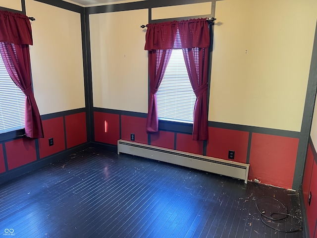 spare room featuring a wainscoted wall, a baseboard radiator, wood-type flooring, and a decorative wall