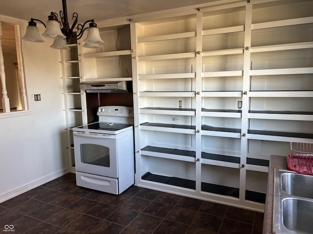 kitchen with white electric range, dark tile patterned flooring, a sink, and baseboards