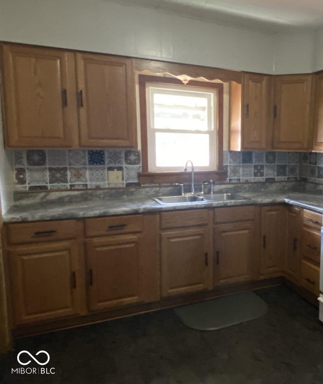 kitchen featuring tasteful backsplash, dark countertops, a sink, and brown cabinets