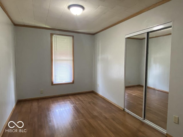 unfurnished bedroom with baseboards, a closet, dark wood finished floors, and crown molding