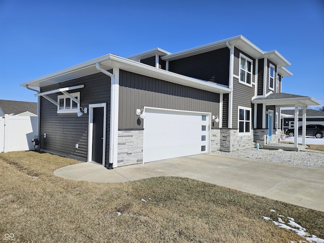 view of front of home featuring a garage, stone siding, a front lawn, and concrete driveway