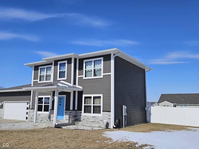 view of front of house featuring a garage, stone siding, and fence