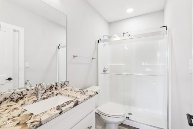 bathroom featuring toilet, a stall shower, and vanity