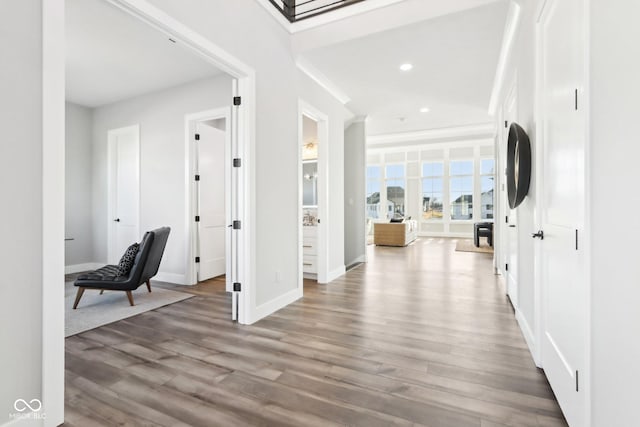 hallway featuring light wood finished floors, baseboards, and recessed lighting