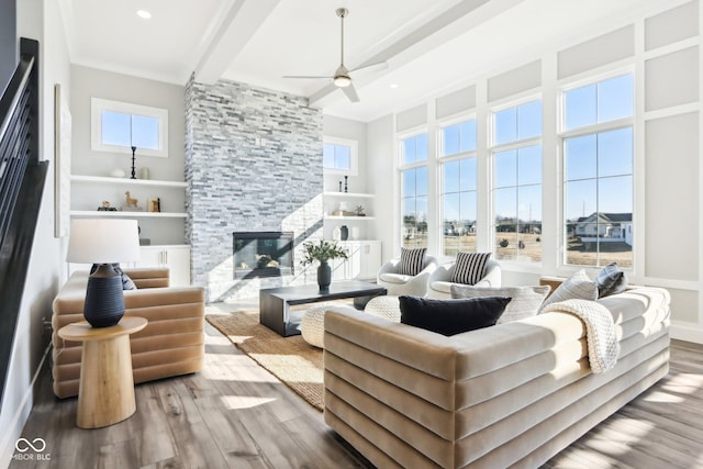 living room featuring a stone fireplace, recessed lighting, a ceiling fan, beam ceiling, and light wood finished floors