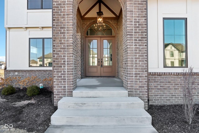 view of exterior entry featuring french doors and brick siding