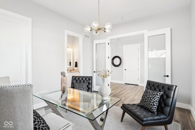 office area with light wood-style floors, baseboards, visible vents, and a chandelier